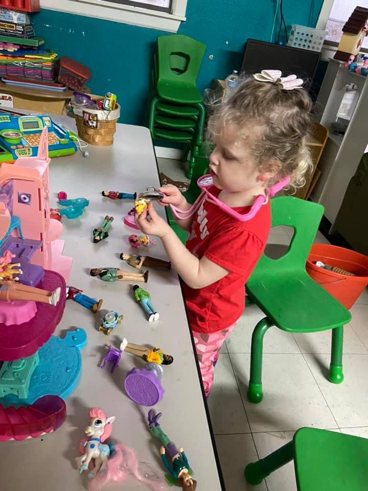 Child playing with toys and a toy stethoscope at a table