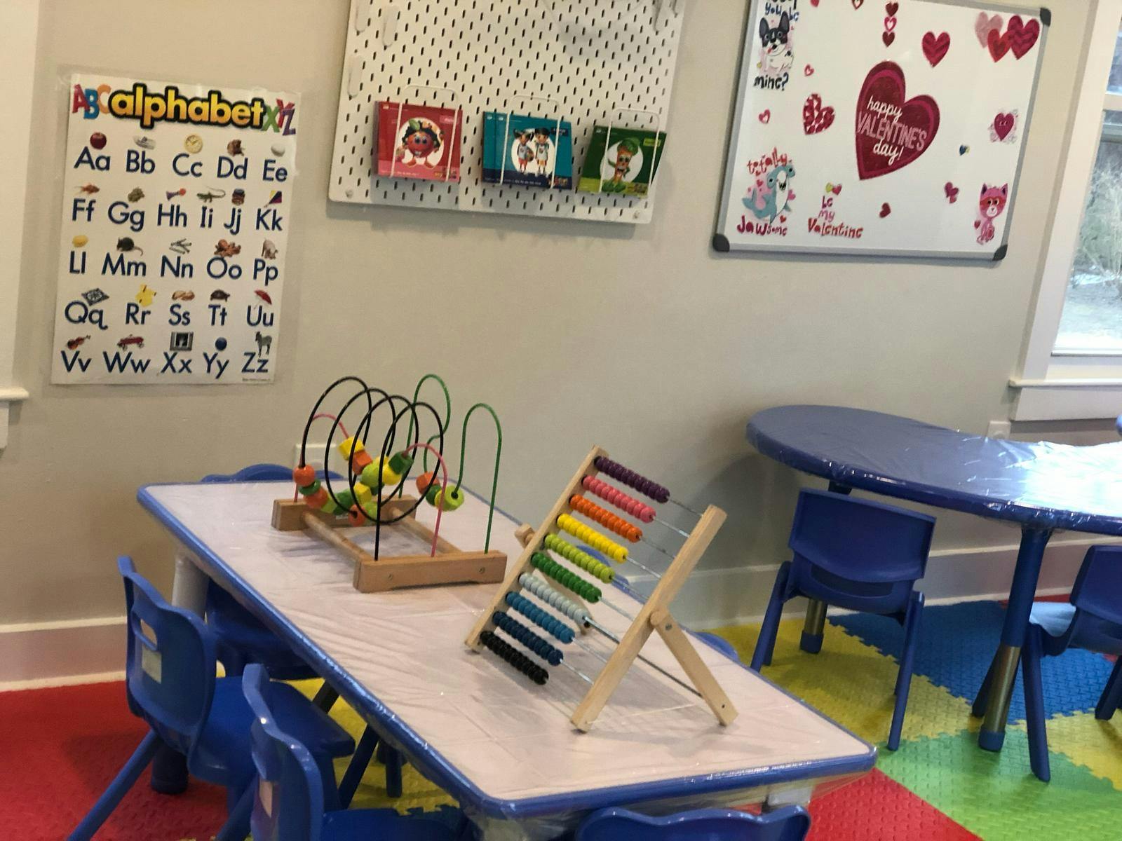 Classroom with alphabet chart, whiteboard, and children's tables with toys