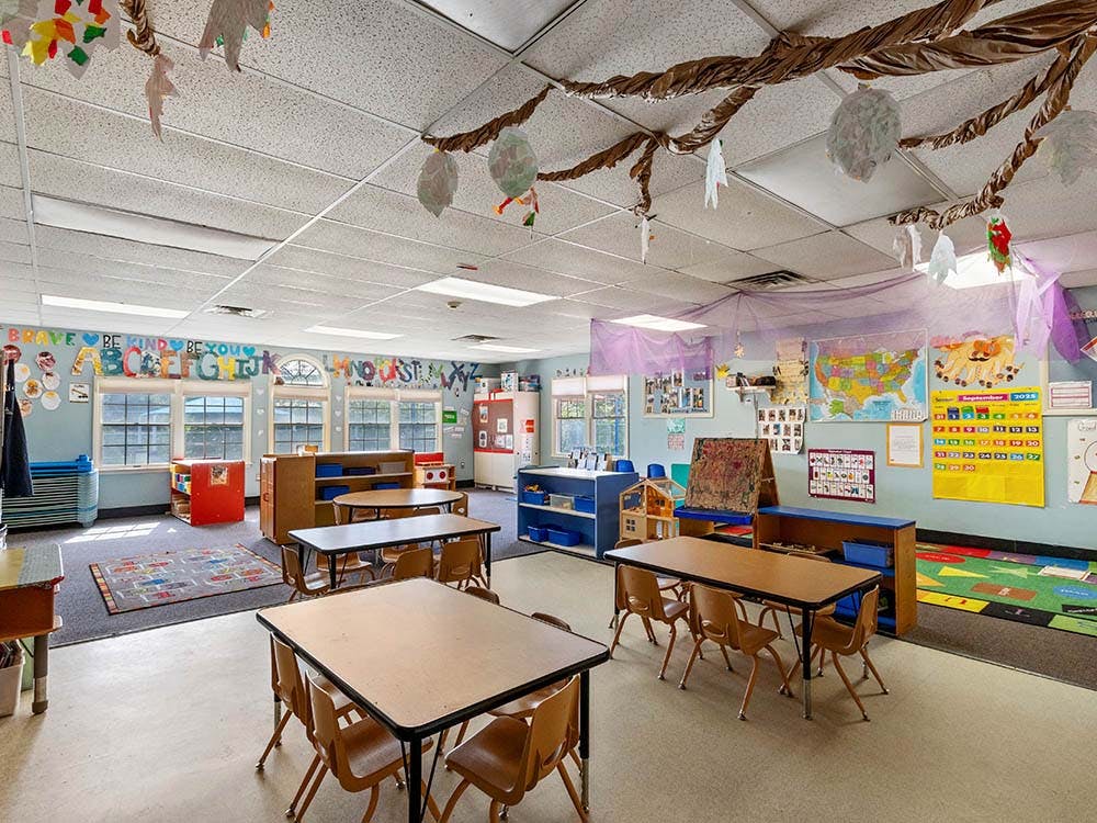 An empty classroom with small tables and chairs, decorated walls and ceiling