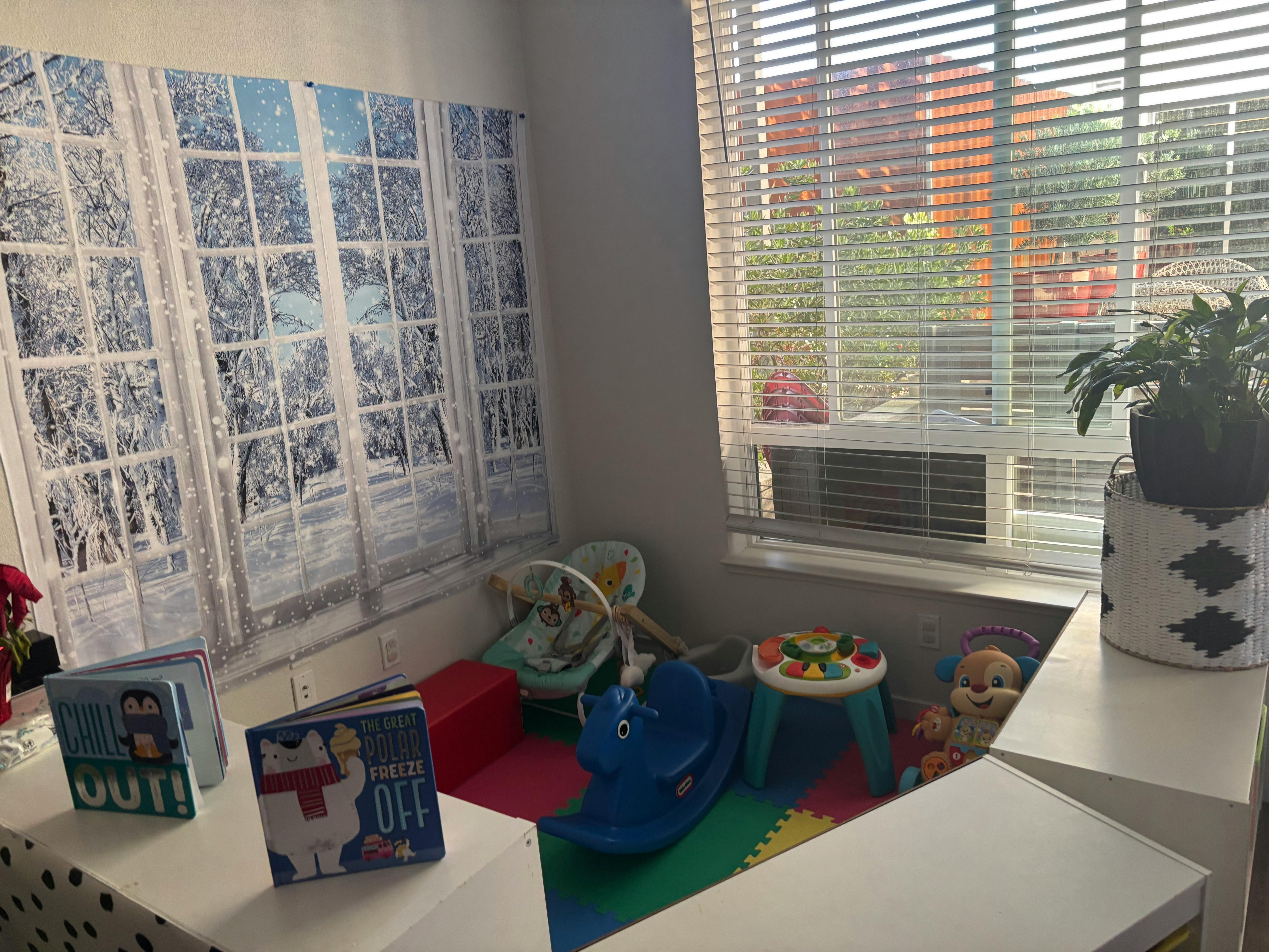 Play area with toys, books, and a window with blinds