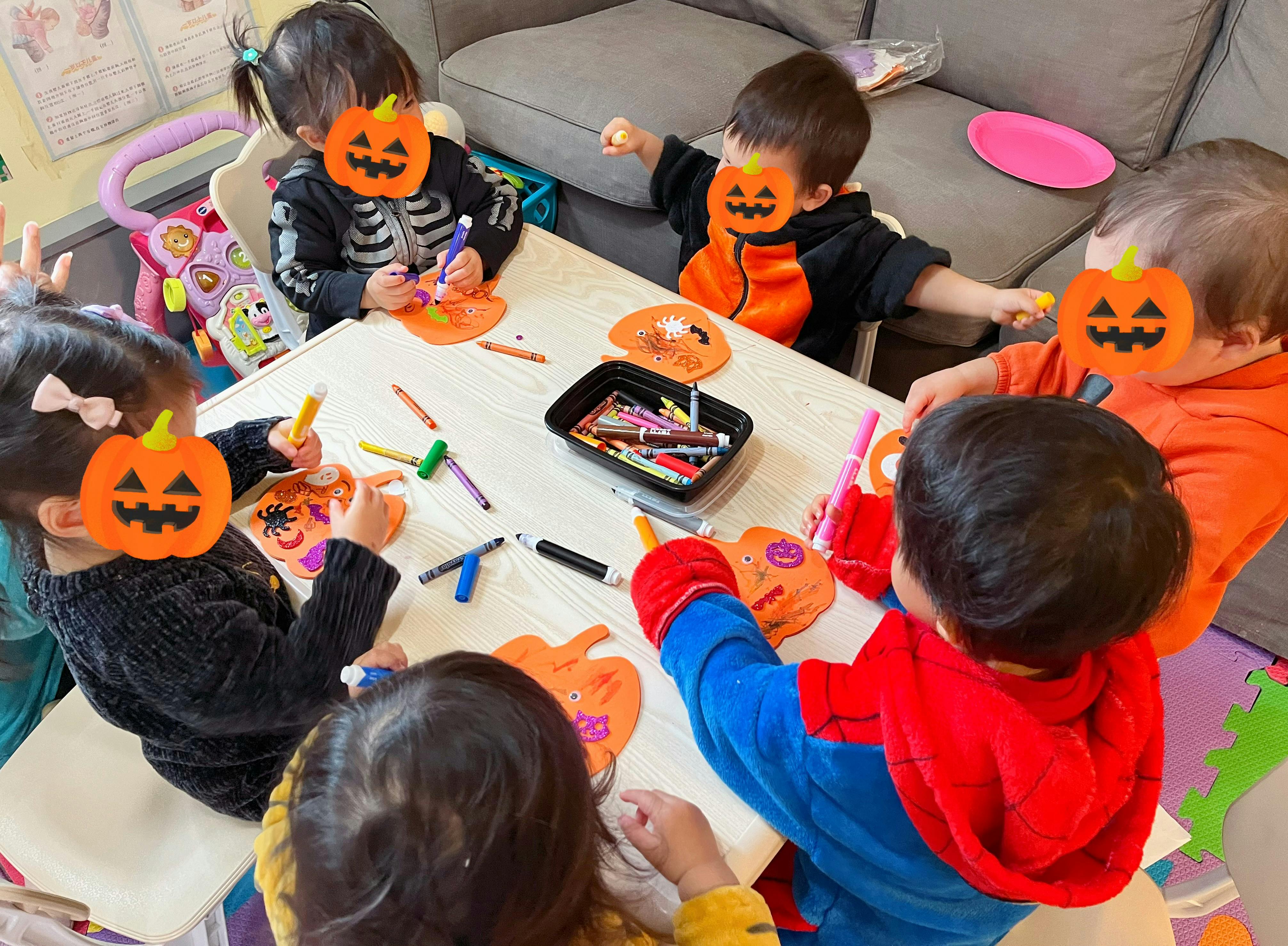 Children at a table doing crafts with pumpkin cutouts
