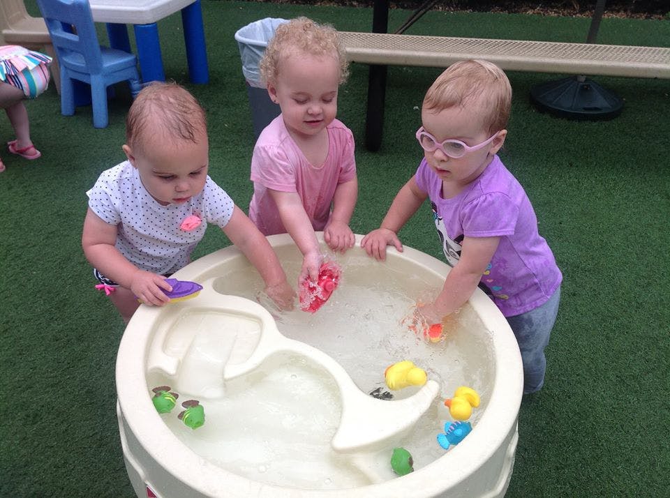 Three children playing with toys in a water table