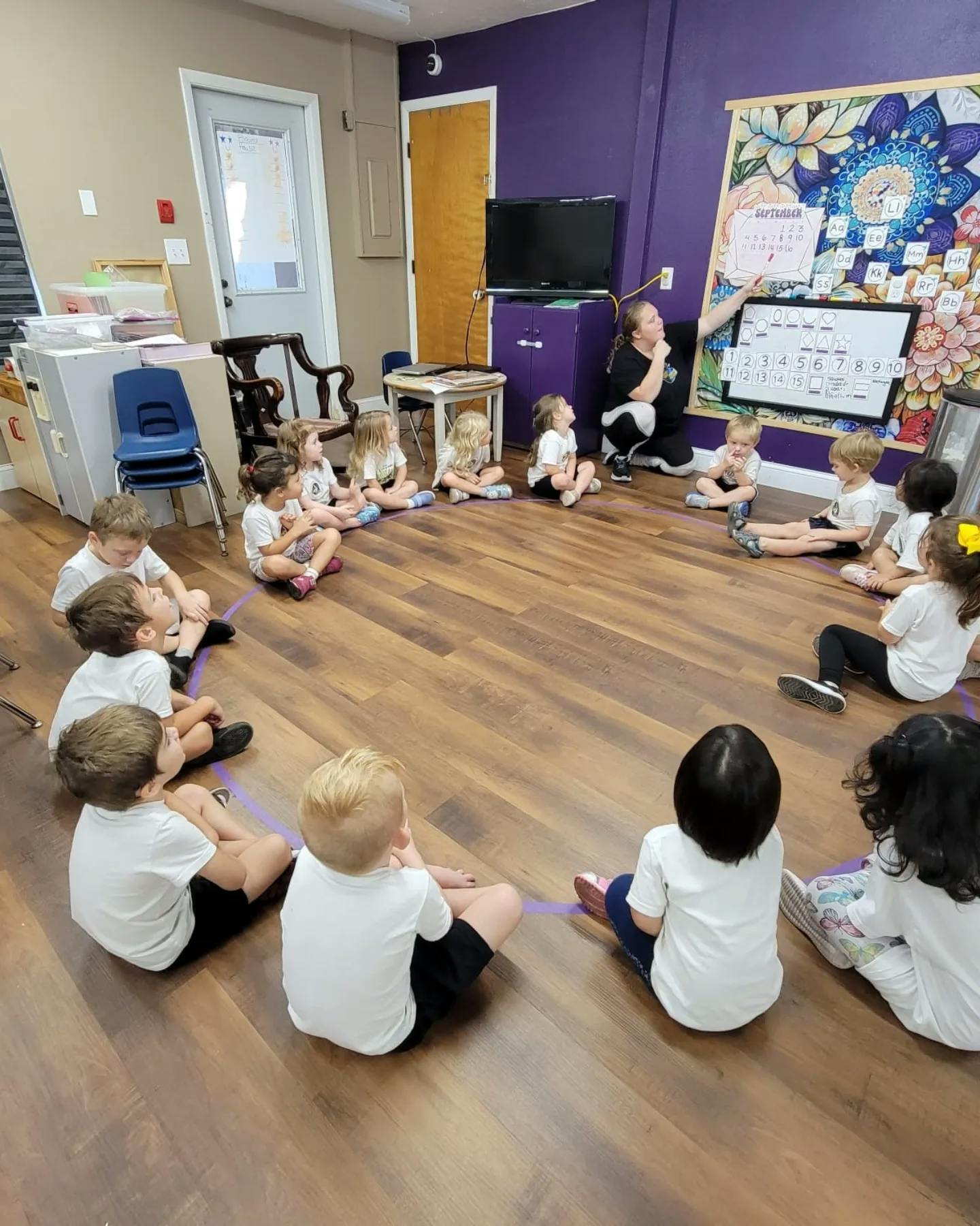Person teaching children sitting in a circle on the floor in a classroom