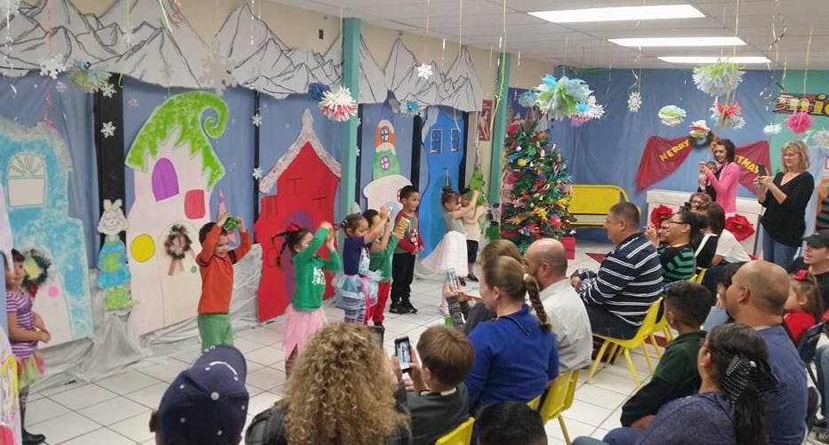 Children performing on a stage with adults watching