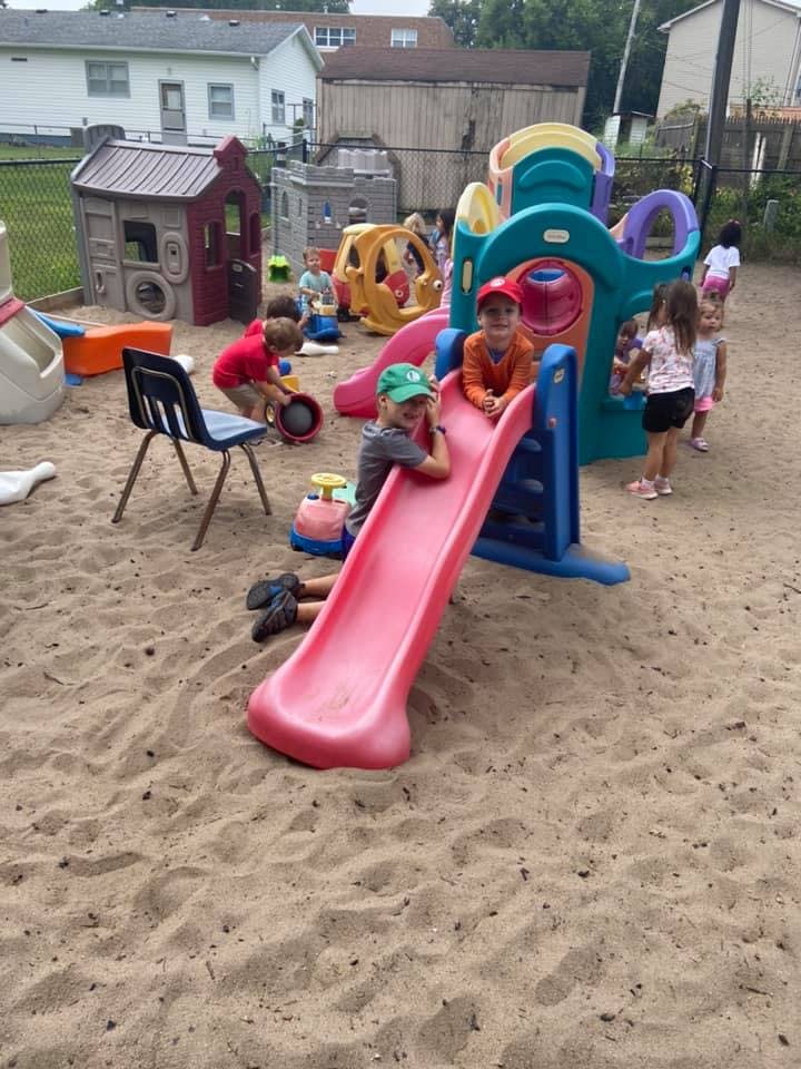 Children playing on a slide and in a sandbox at a playground