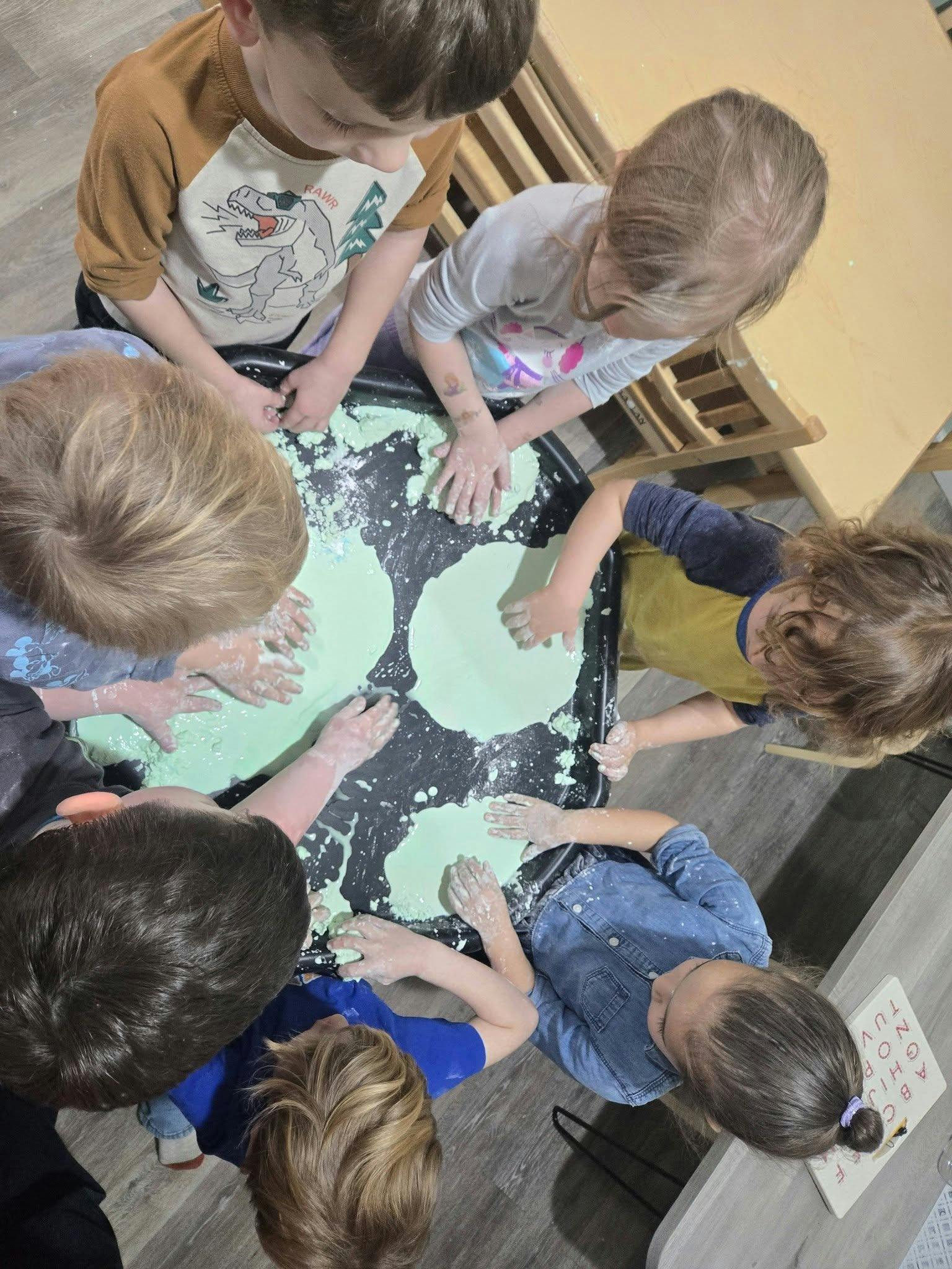 Group of children playing in green slime at a table