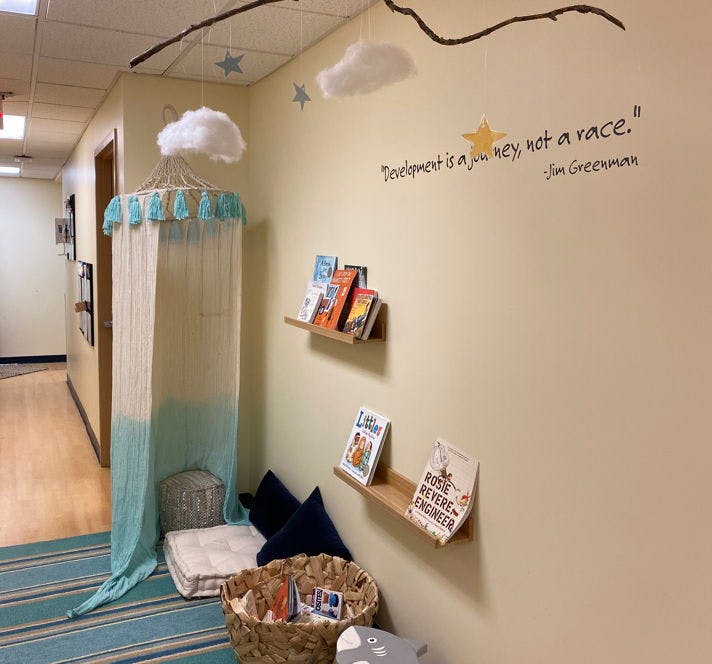 Reading nook with canopy, floor cushions, and books on wall shelves