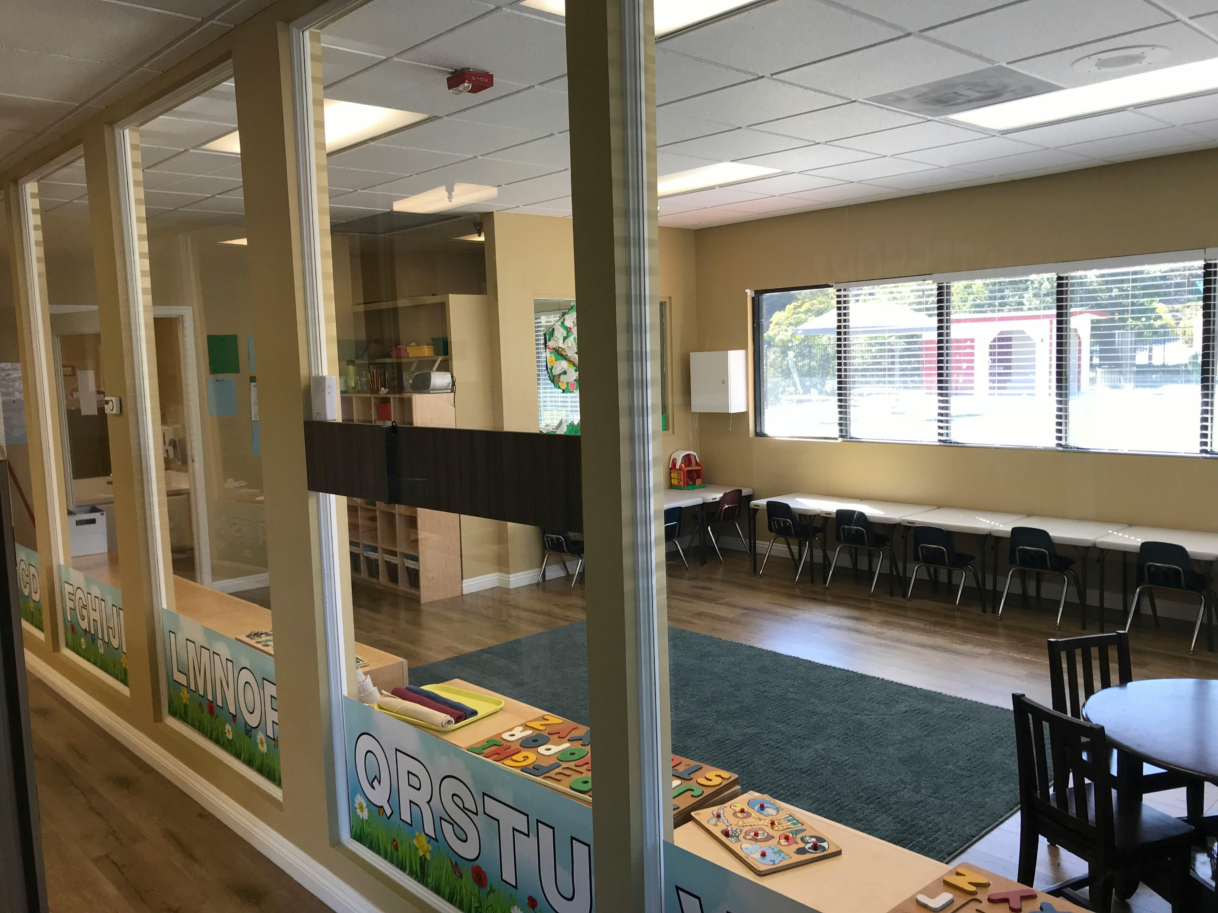 Classroom with tables and chairs, seen through a glass partition