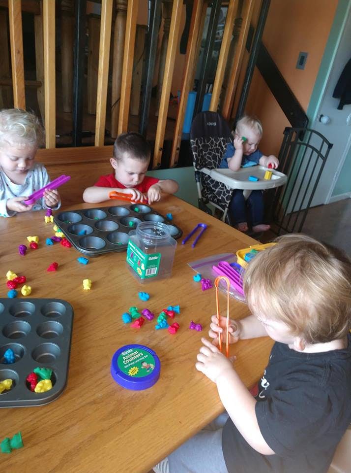 Multiple children playing with colorful counters and muffin tins at a table
