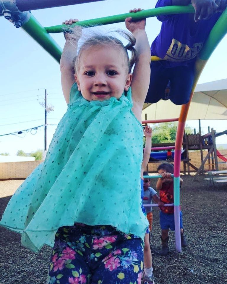 Child hanging from monkey bars on a playground