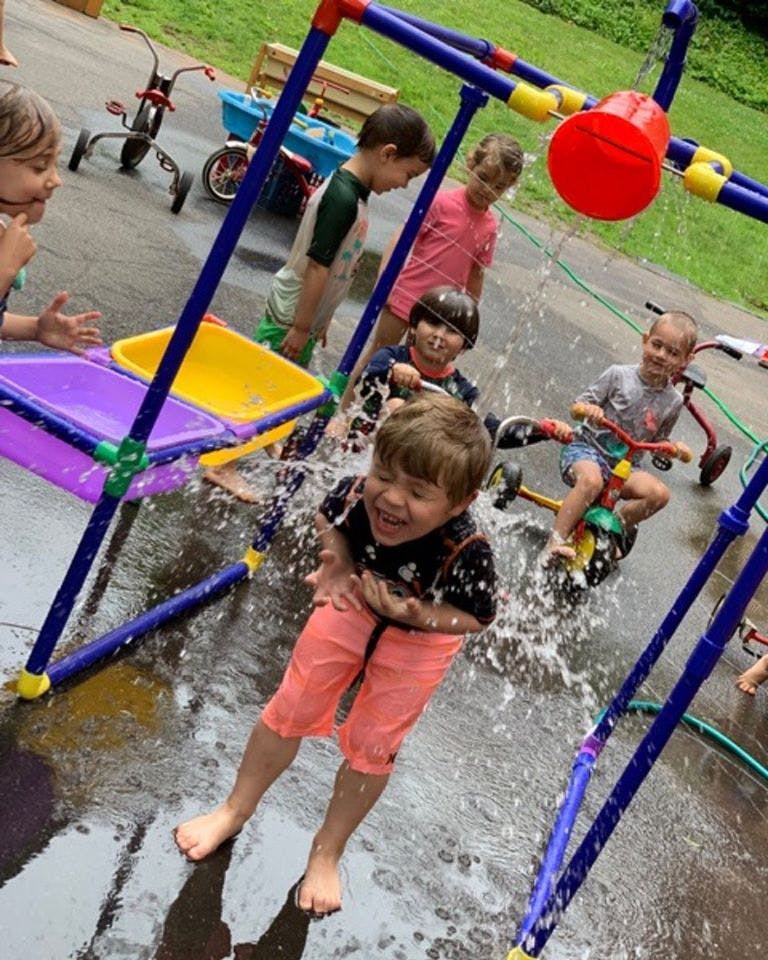 Children playing in water from a colorful outdoor water table