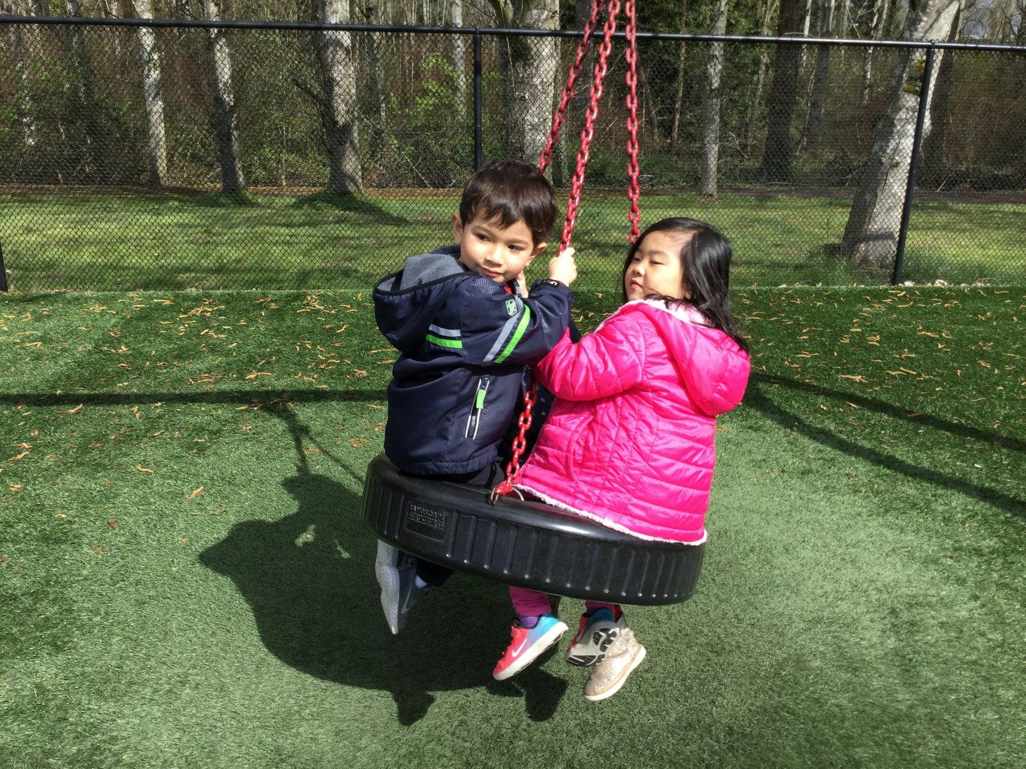 Two children on a tire swing