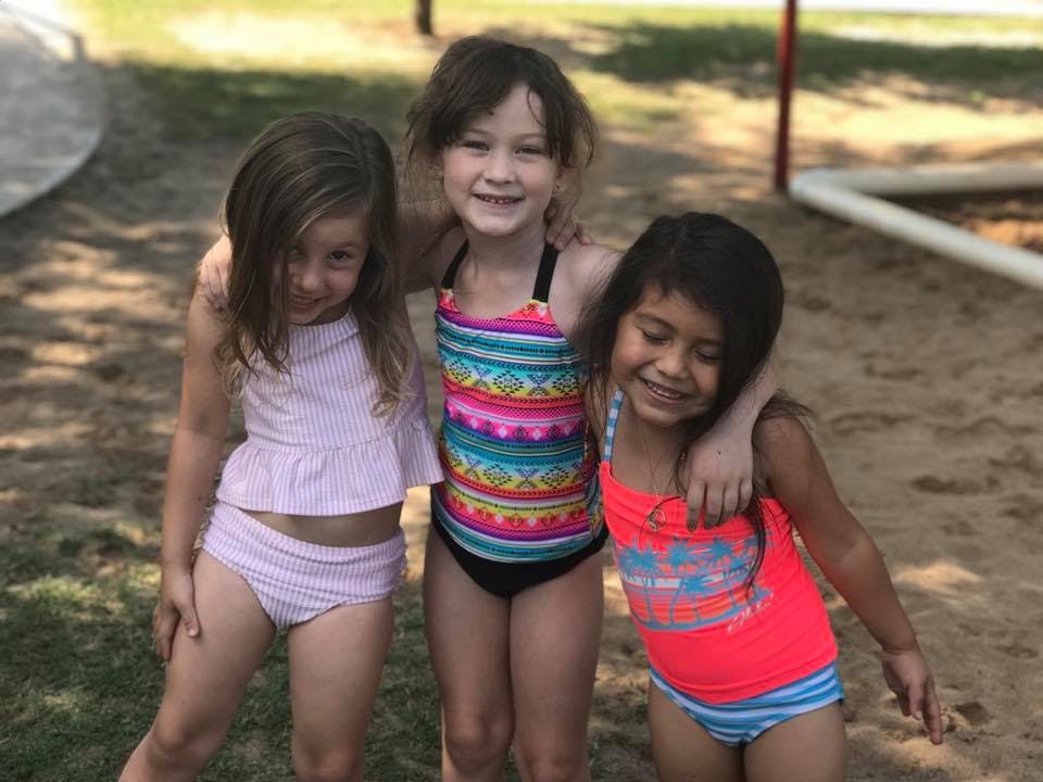 Three children in swimsuits standing together
