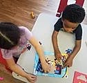 Two children assembling a puzzle on a table