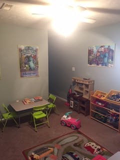 Playroom with small table and chairs, toy shelves, and rug