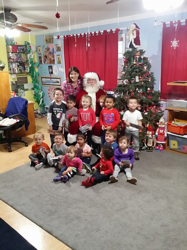 Person dressed as Santa Claus with an adult and multiple children