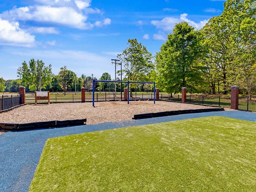 Empty playground with blue swing set on wood chips and artificial turf