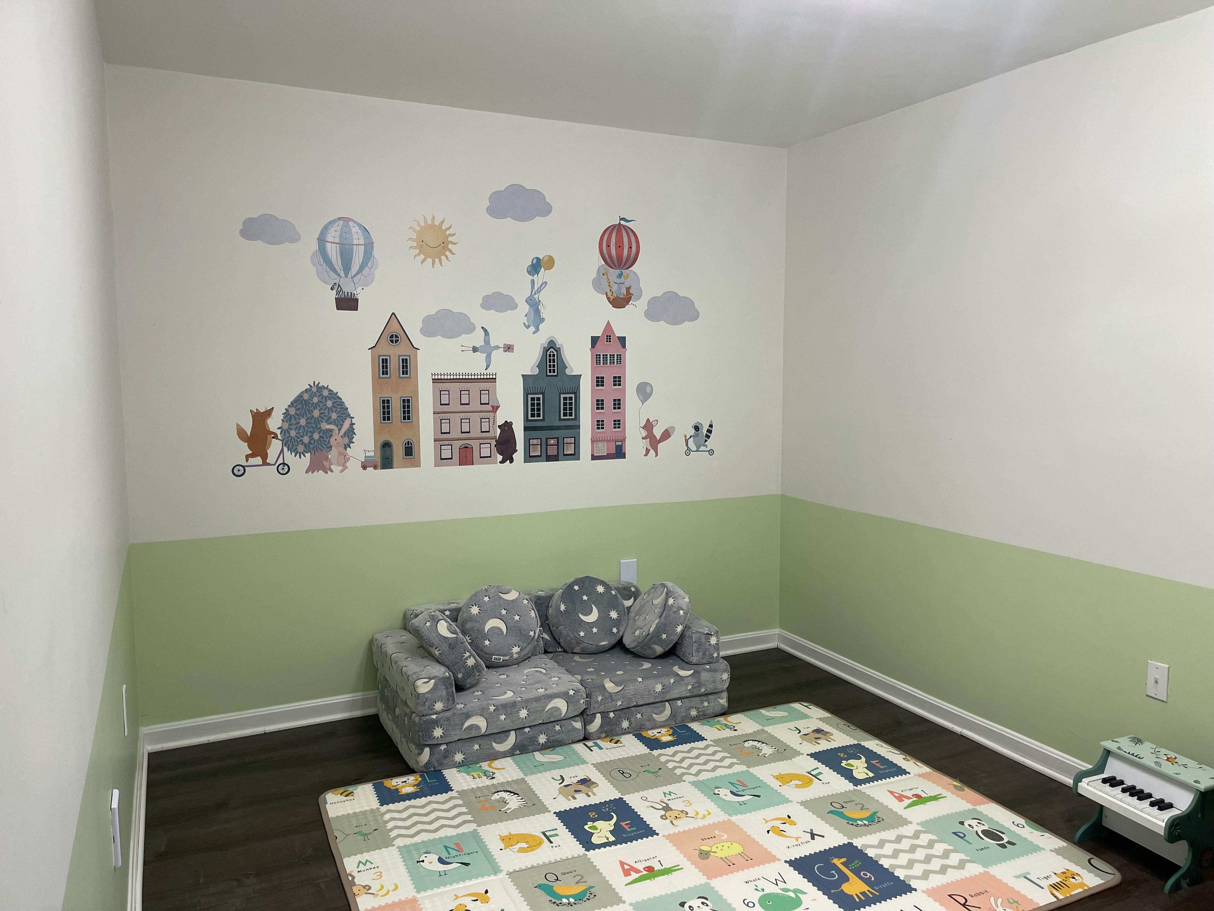 Playroom with wall decals, sofa, and playmat