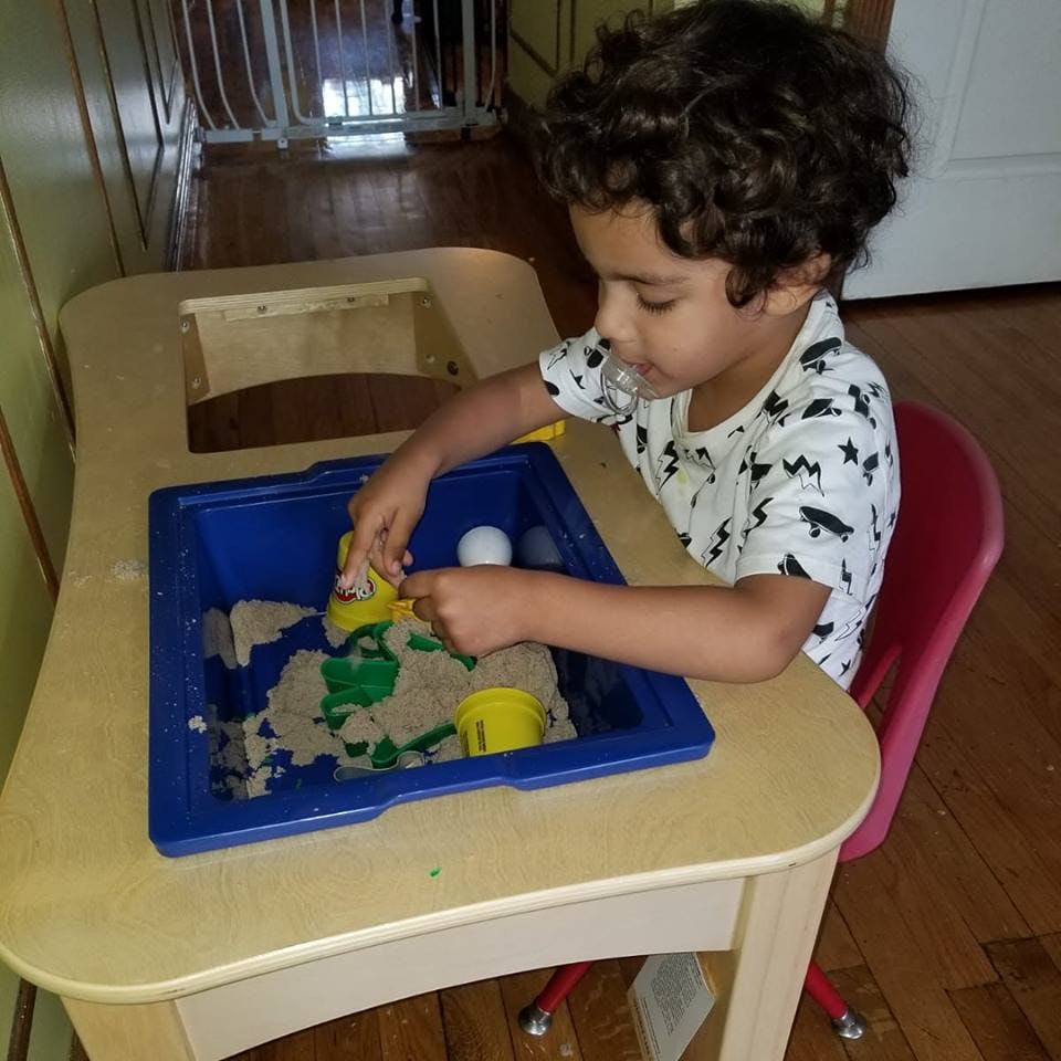 Child playing with kinetic sand at a small table