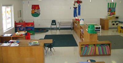 Classroom with small tables, chairs, and shelves with colorful decorations