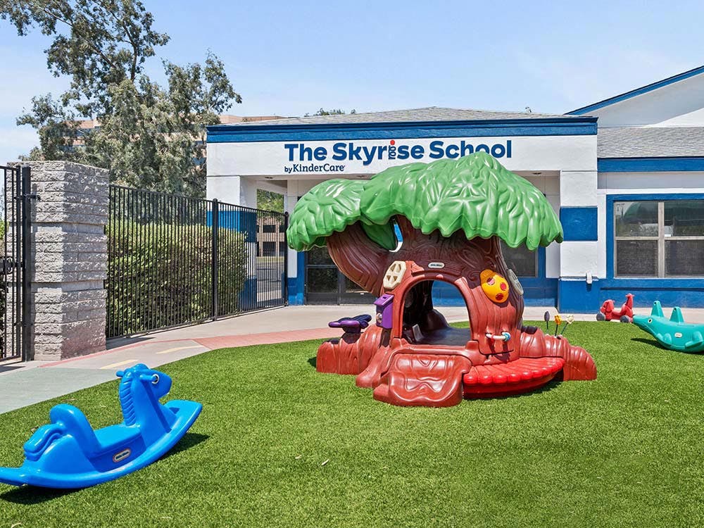 The Skyrise School building with a play area and toys on artificial turf