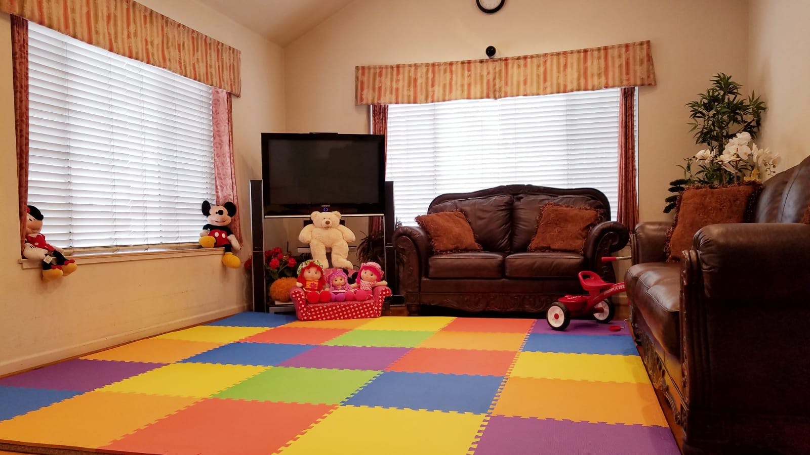 Living room with colorful play mat, sofa, and television
