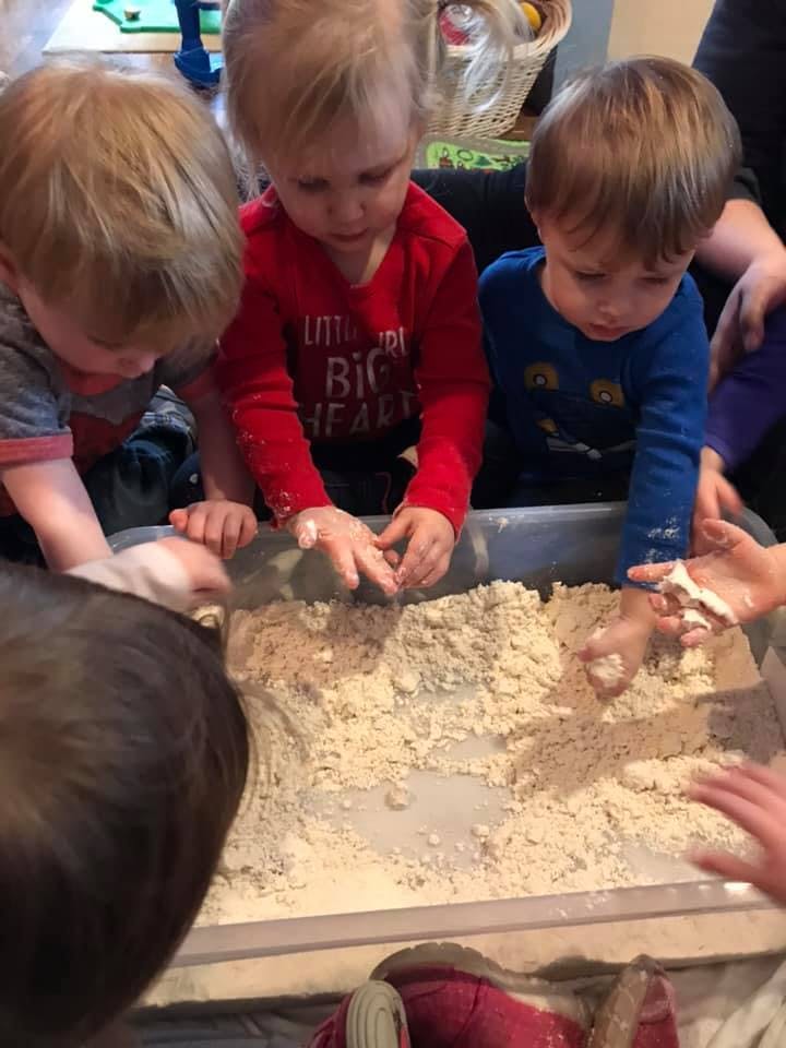 Children playing with sand or dough in a container