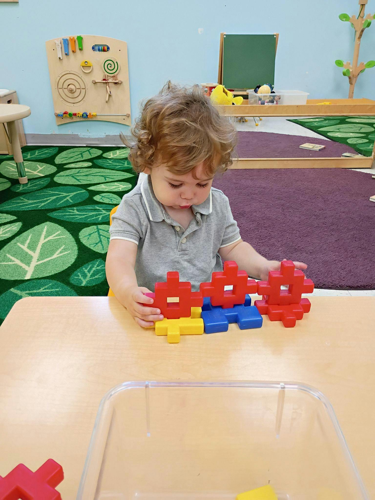 Child building with interlocking plastic blocks at a table