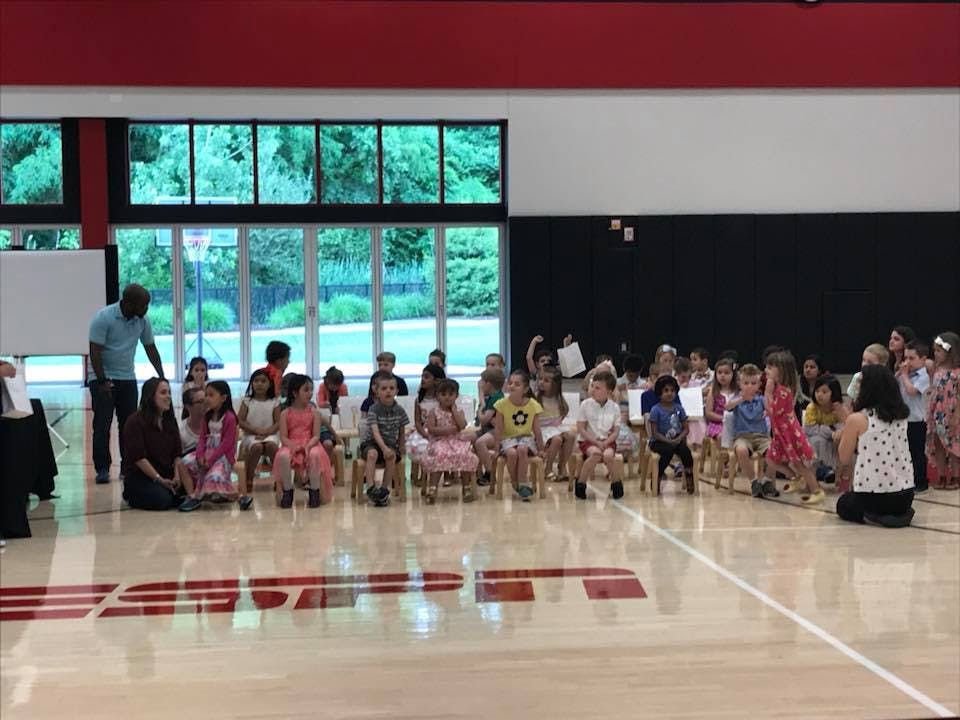 Adults and children sitting and standing in a gymnasium