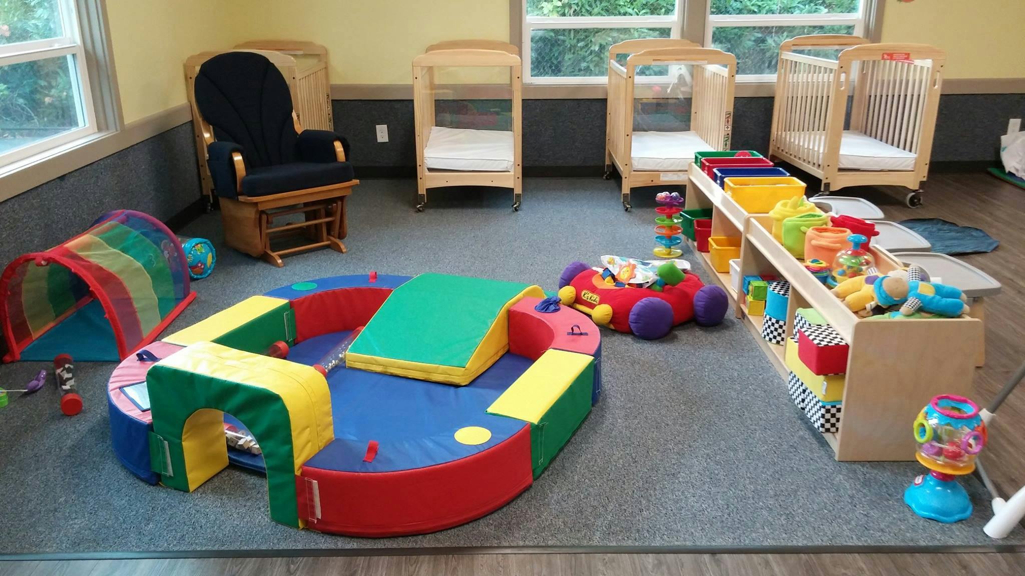 Indoor play area with soft play equipment, cribs, and toys