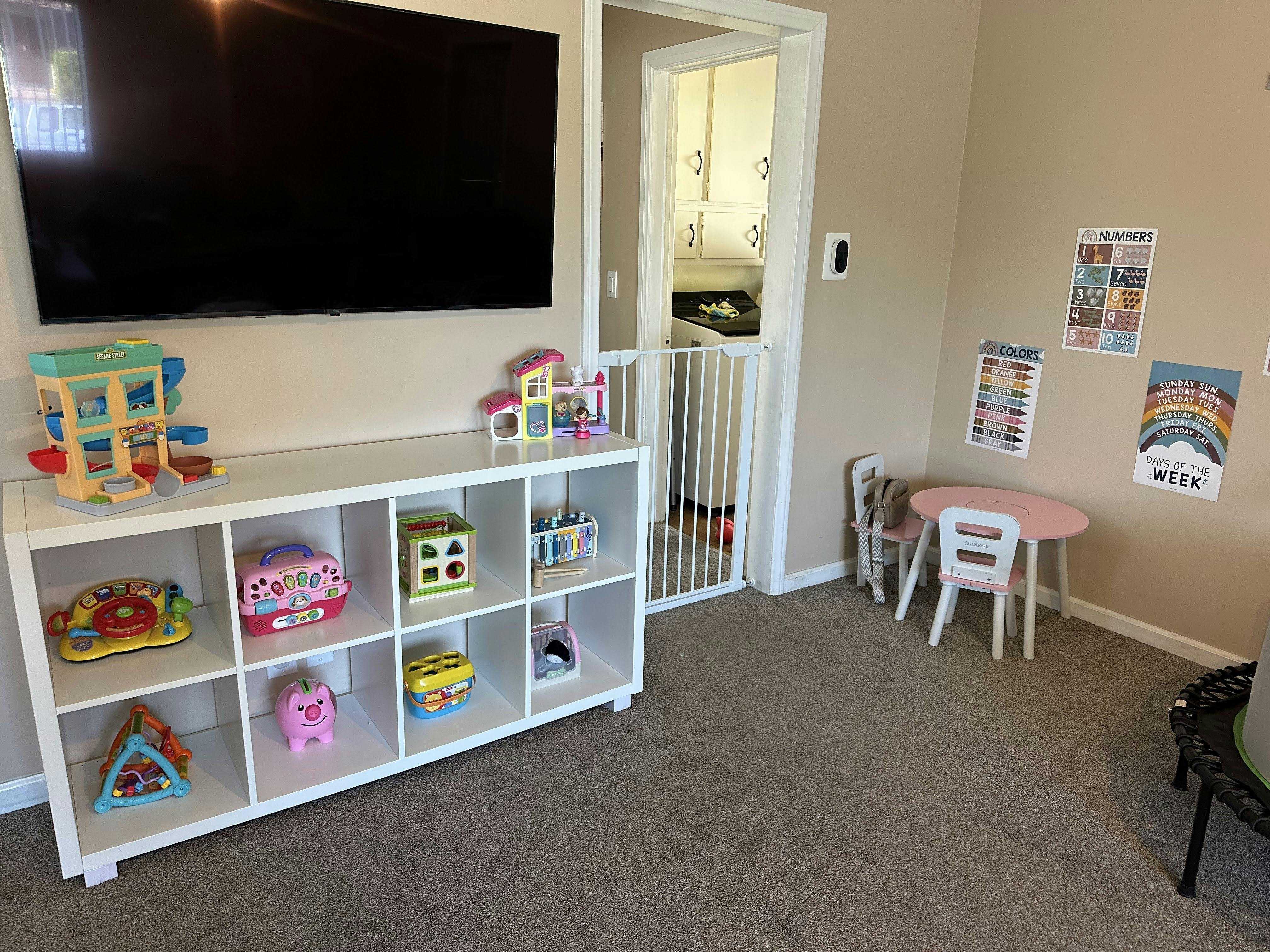 Child's playroom with toys on shelves, small table and chairs, and educational posters