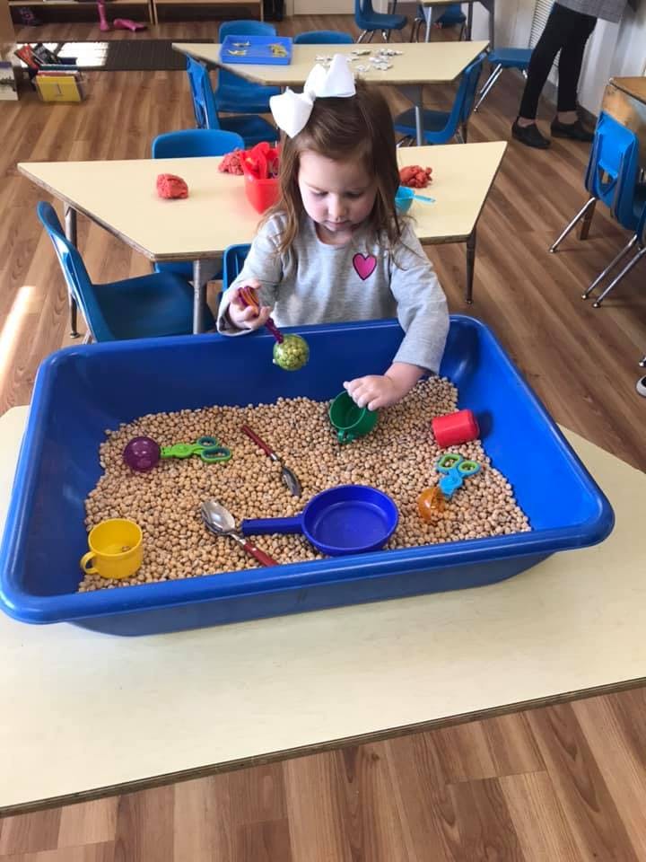 Child playing with sensory bin filled with small objects