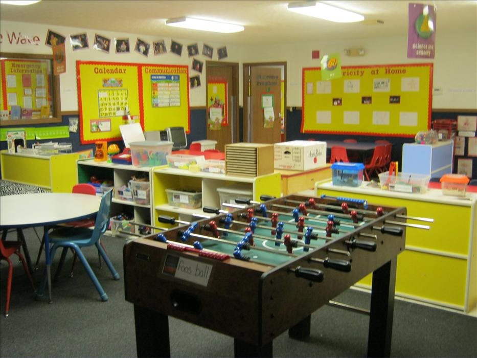 foosball table in a brightly lit classroom with yellow shelves