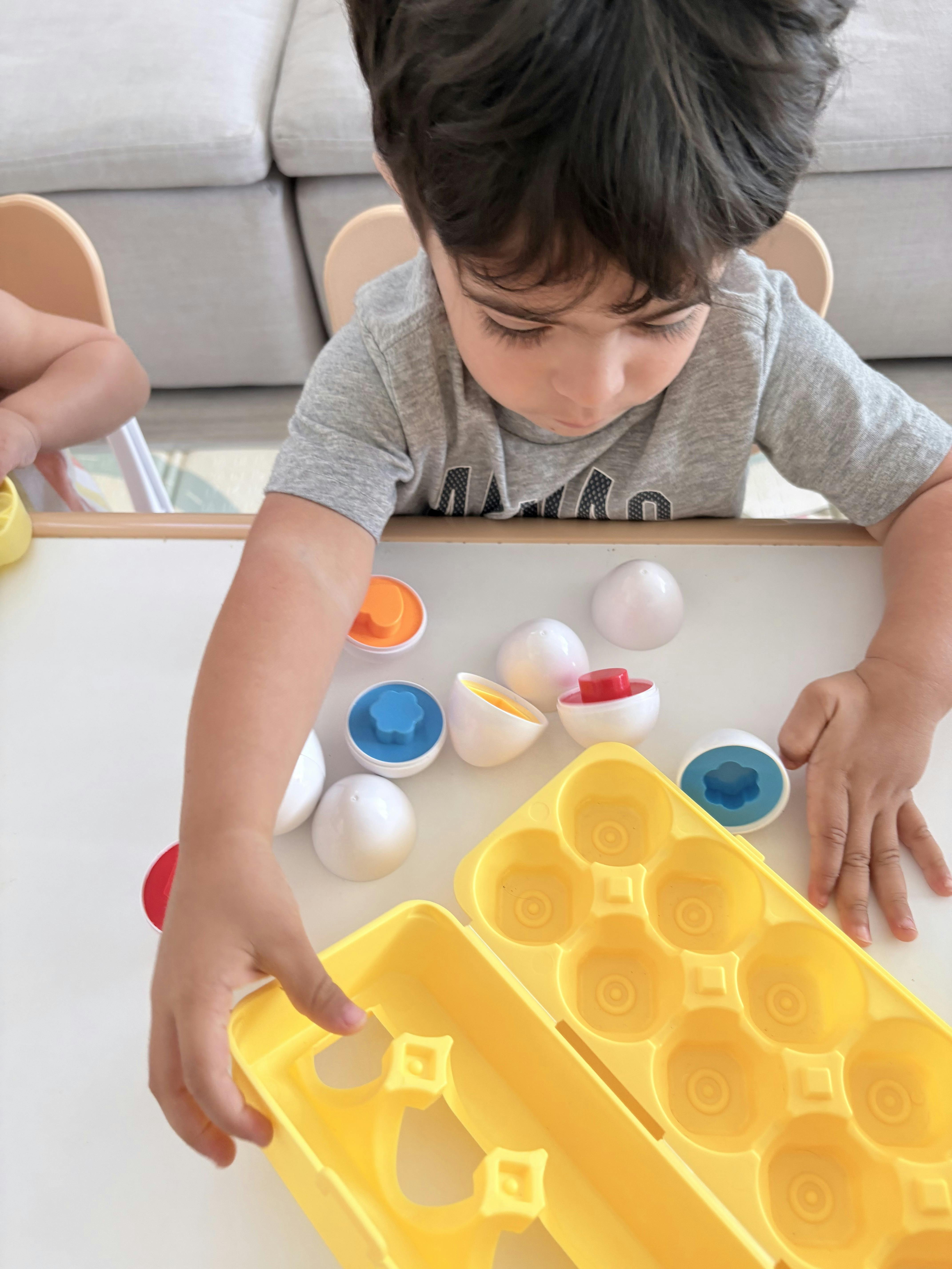 Child playing with matching egg-shaped toys at a table