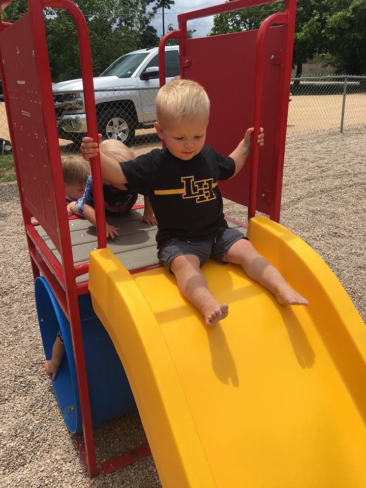 Child sitting on a yellow slide on a playground
