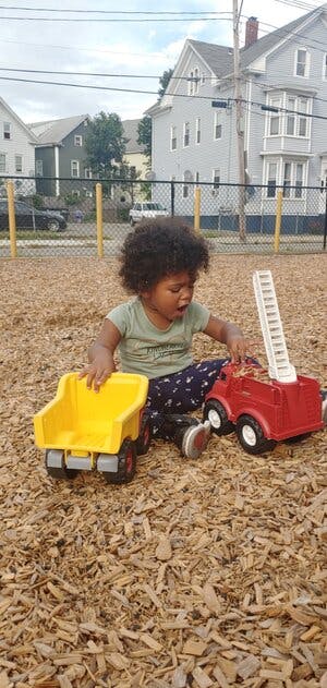 Child playing with toy trucks on wood chips