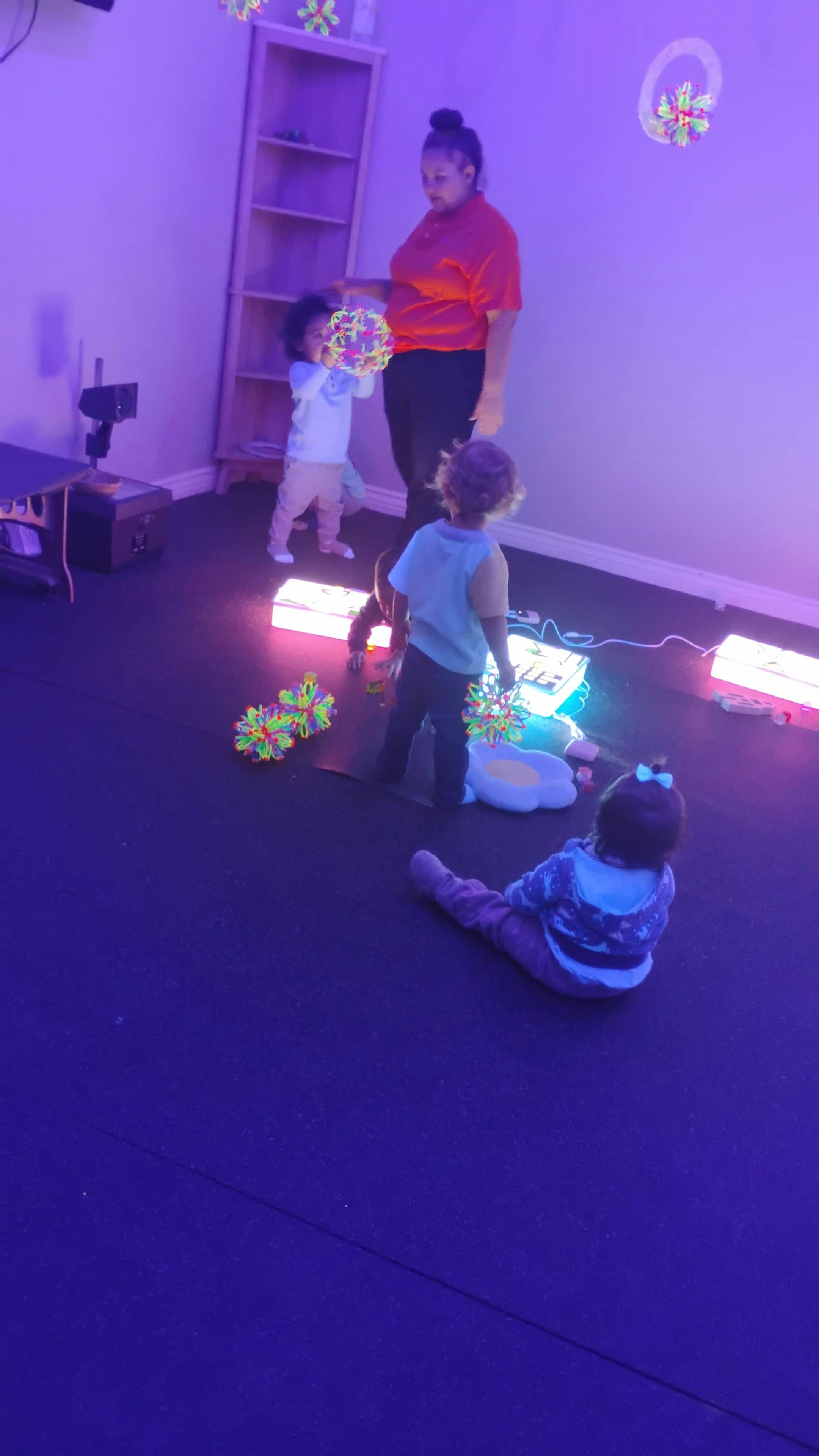 Adult and children playing with glowing objects in a dark room
