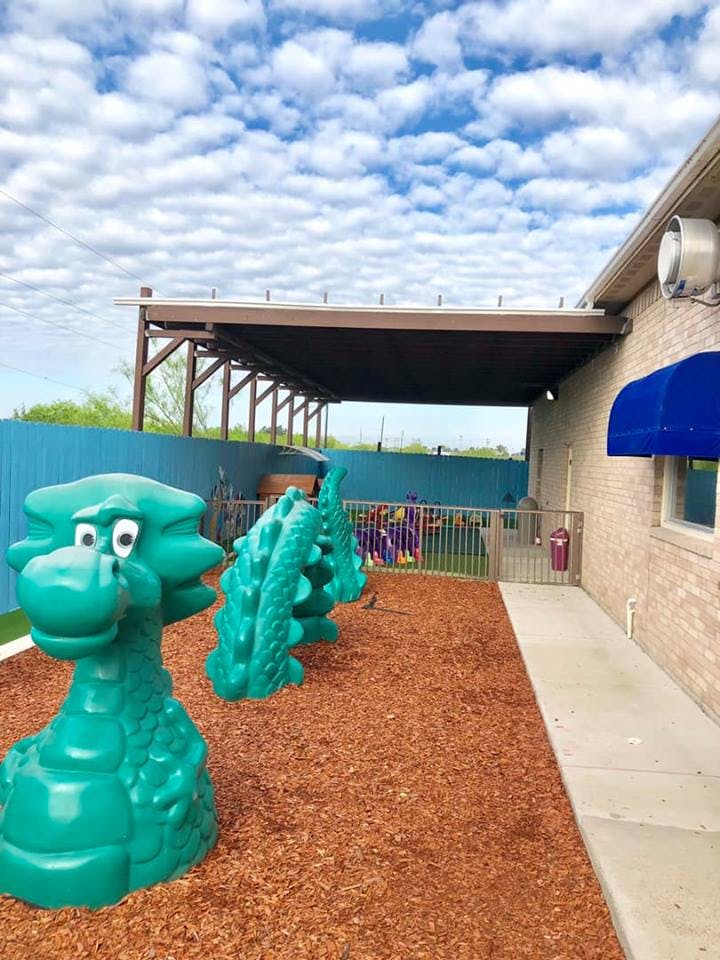 Outdoor play area with green dragon-shaped play equipment on wood chips