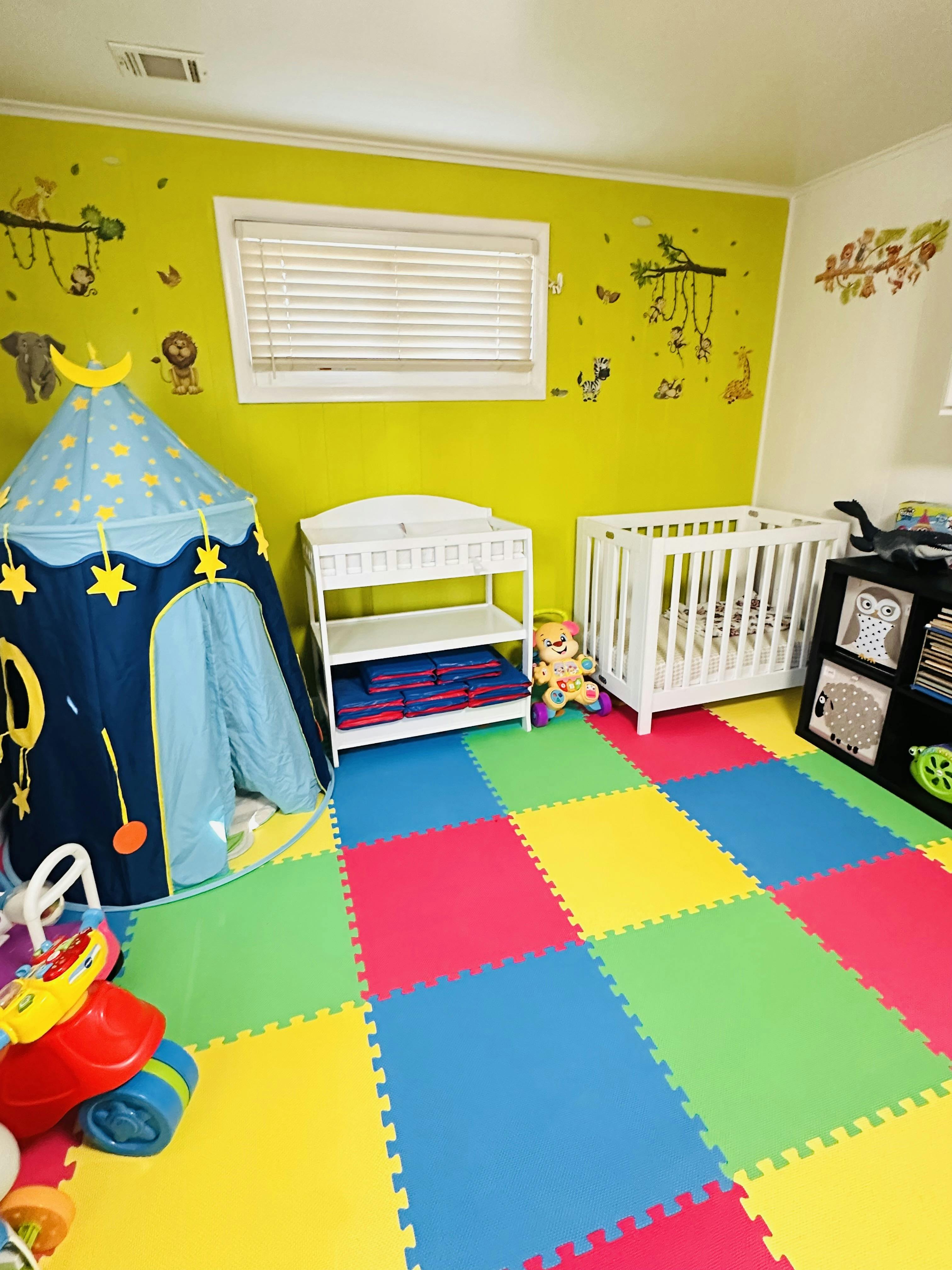 Nursery room with a play tent, changing table, crib, and colorful floor mats