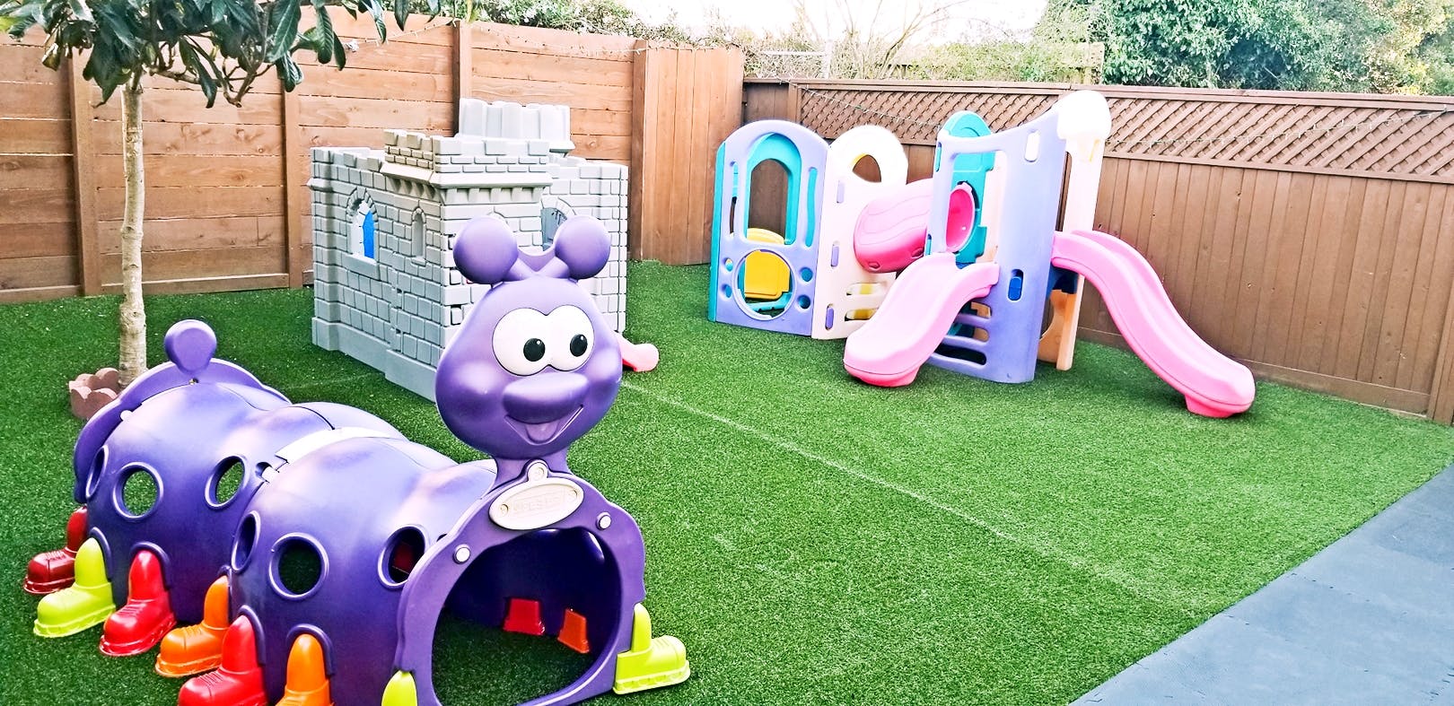 Playground with purple caterpillar tunnel, castle, and colorful slides