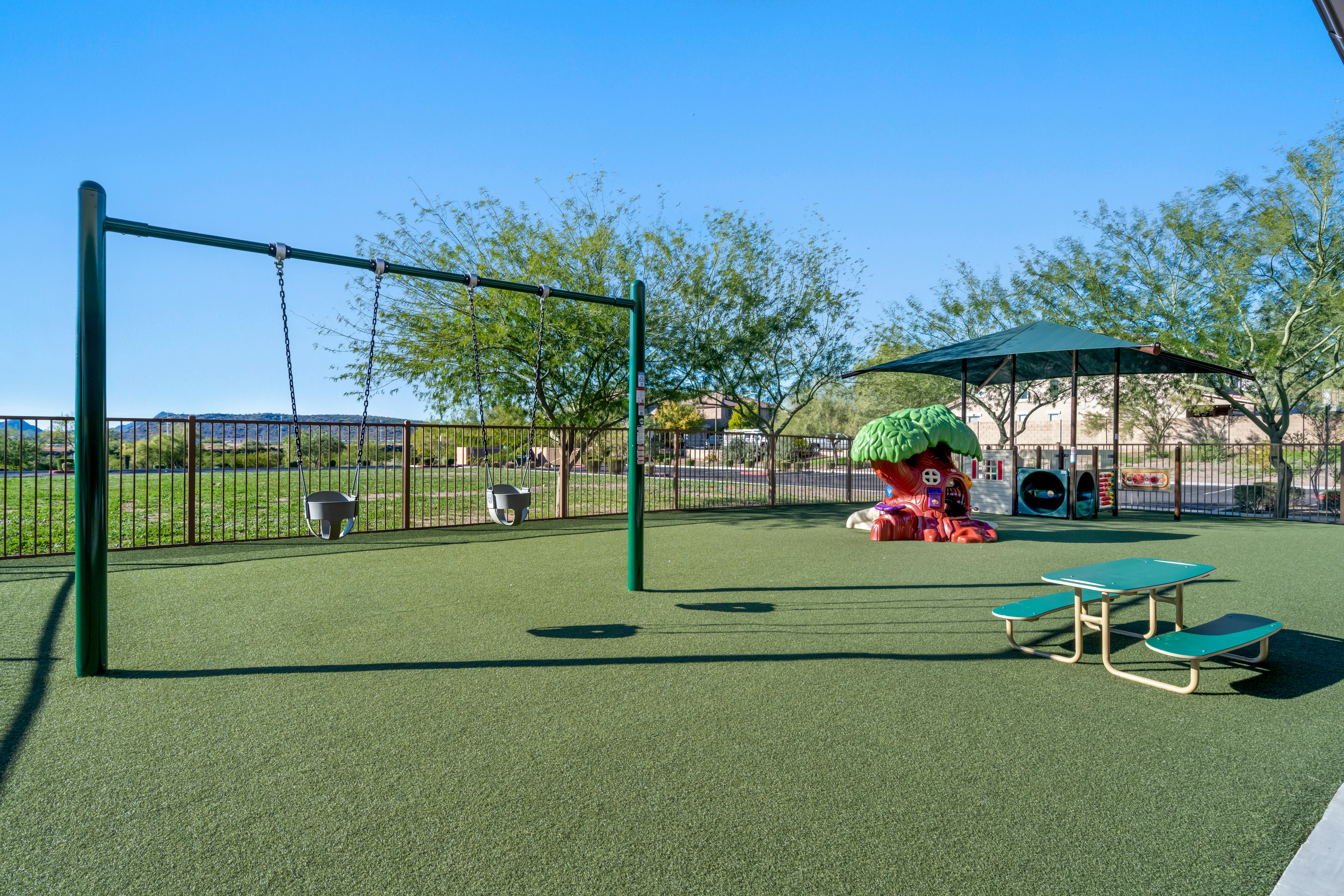 Playground with swings, a play structure, and a small picnic table