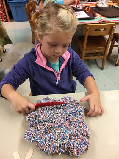 Child playing with colorful textured dough at a table