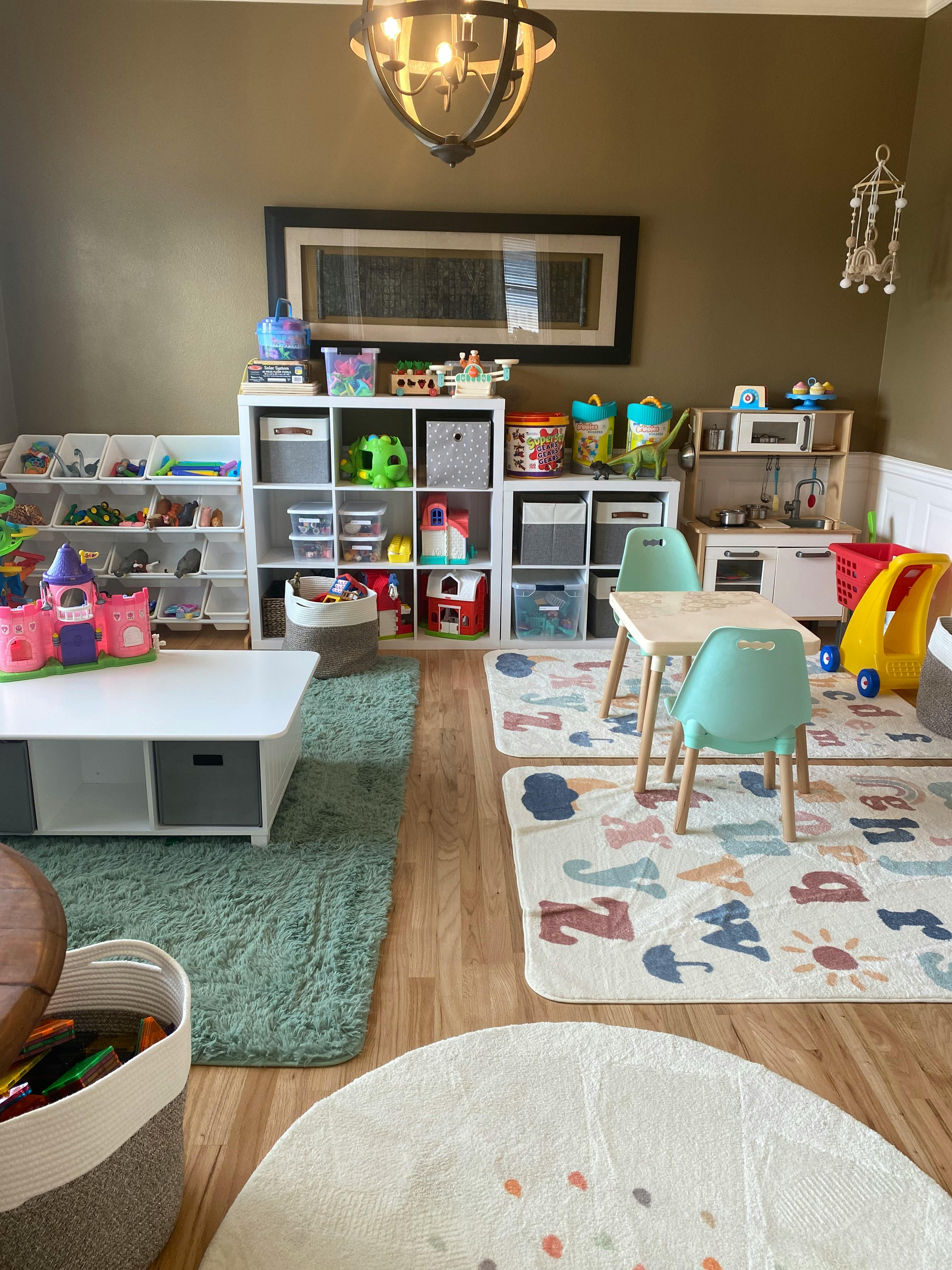 Playroom with toy shelves, small tables and chairs, and alphabet rugs