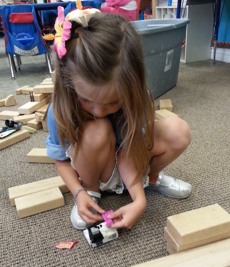 Child playing with a toy car and blocks on the floor