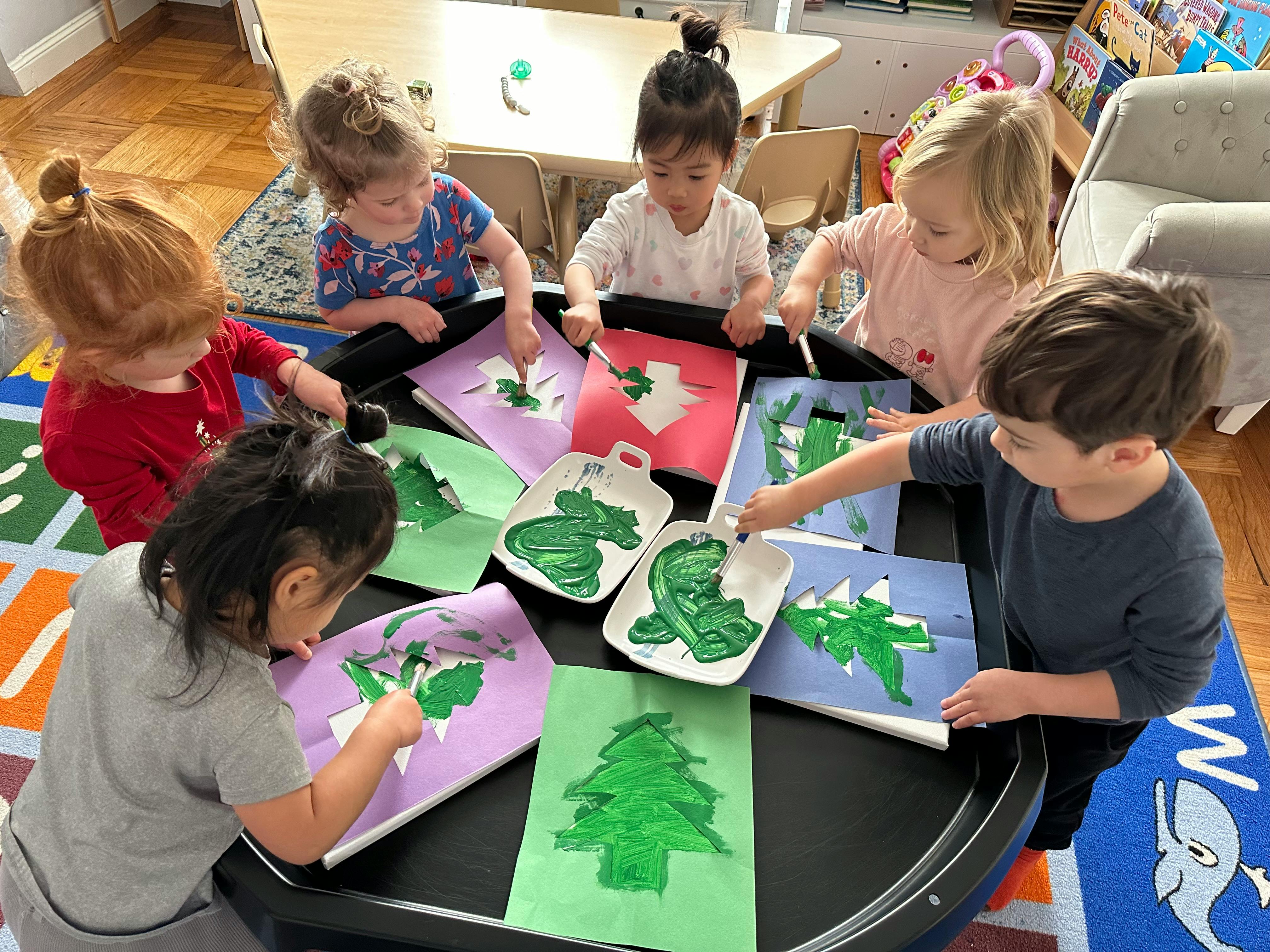Children painting with green paint and stencils