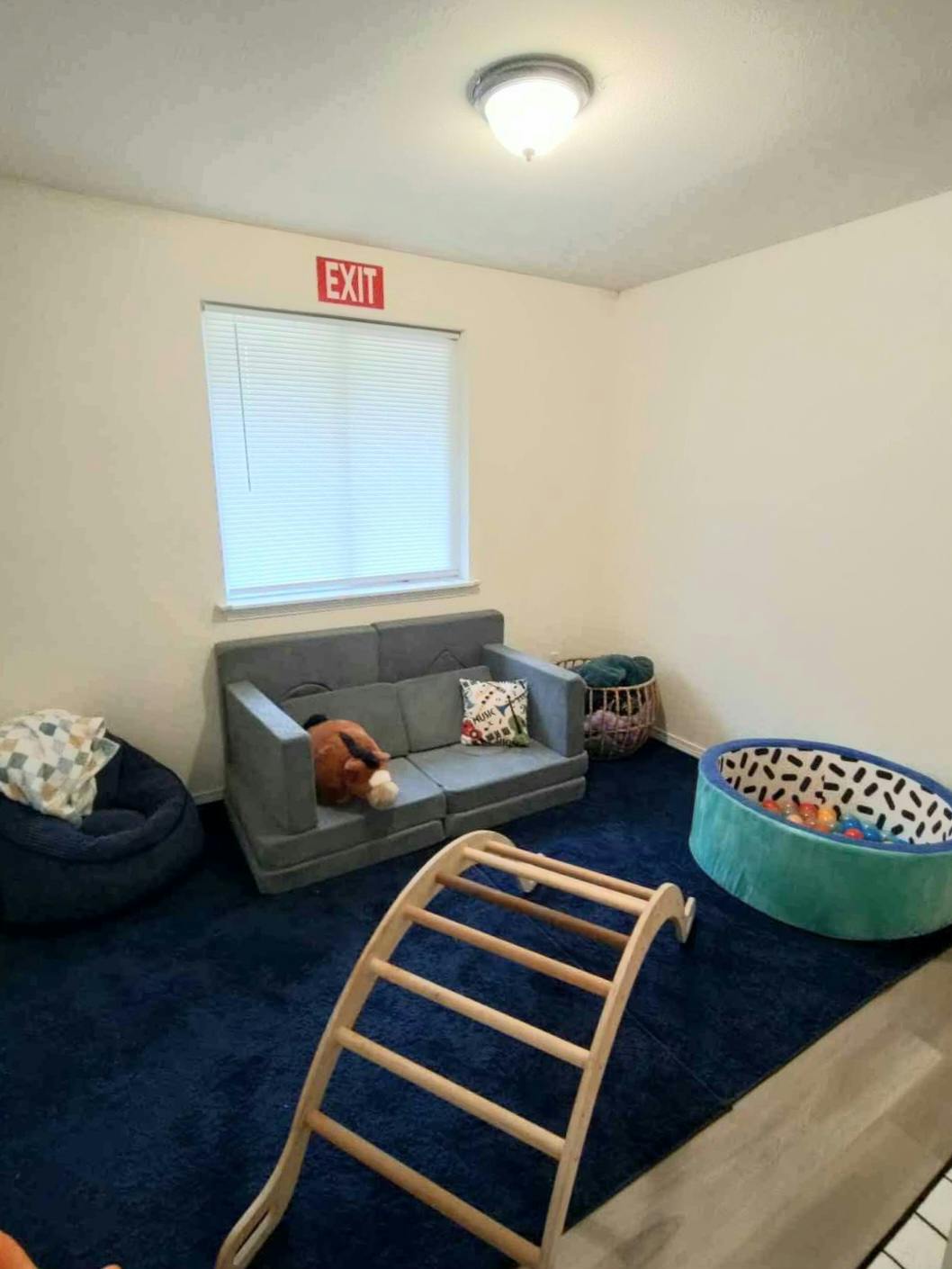Playroom with a sofa, beanbag, ball pit, and wooden climbing arch