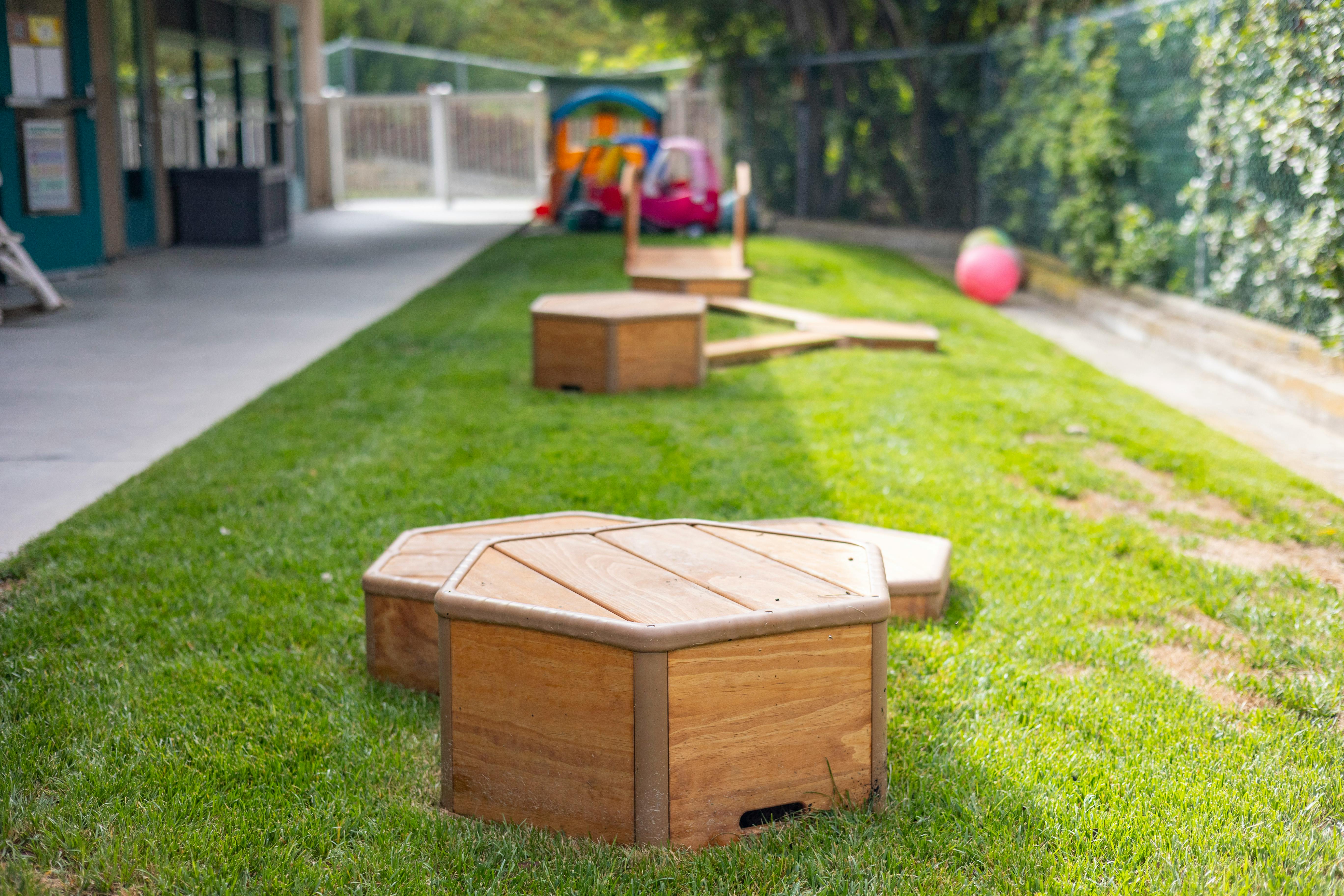 Wooden play structures on a grassy slope next to a building
