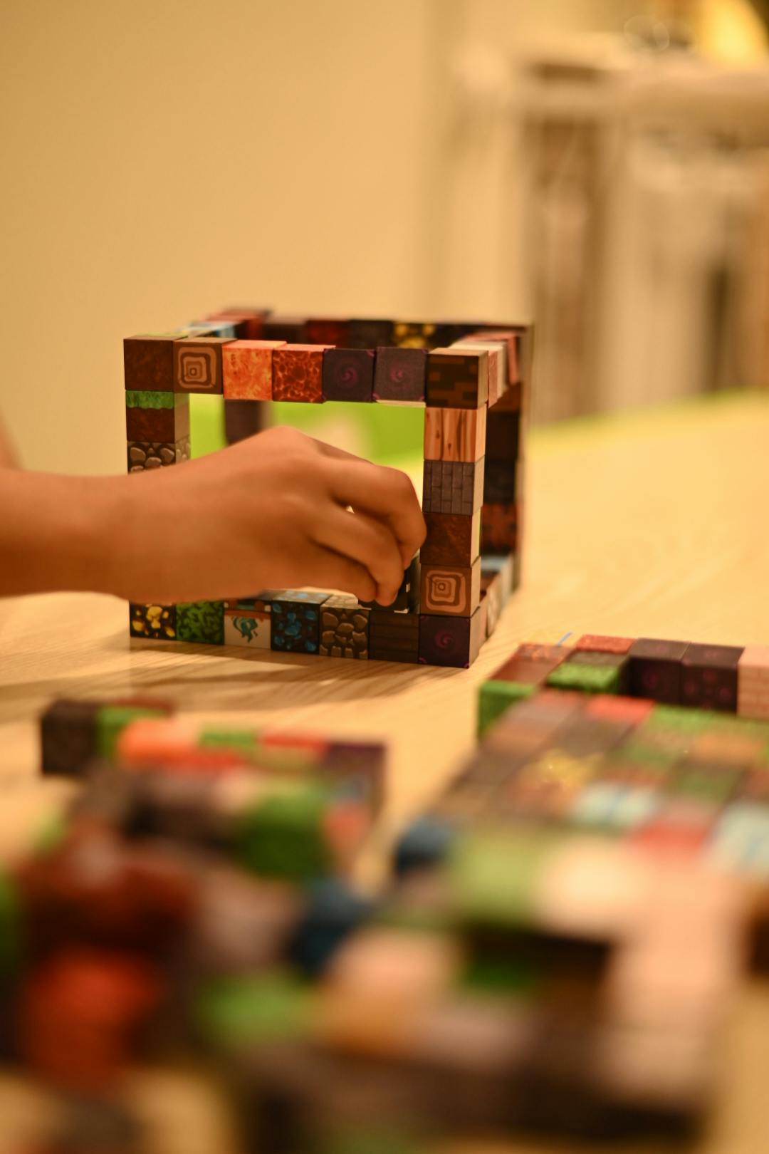 Child's hand building a structure with colorful square blocks