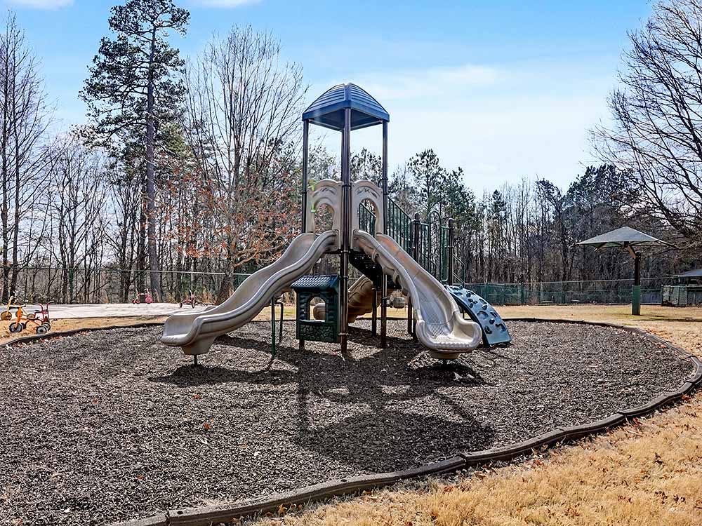 A playground with two slides and wood chips on the ground