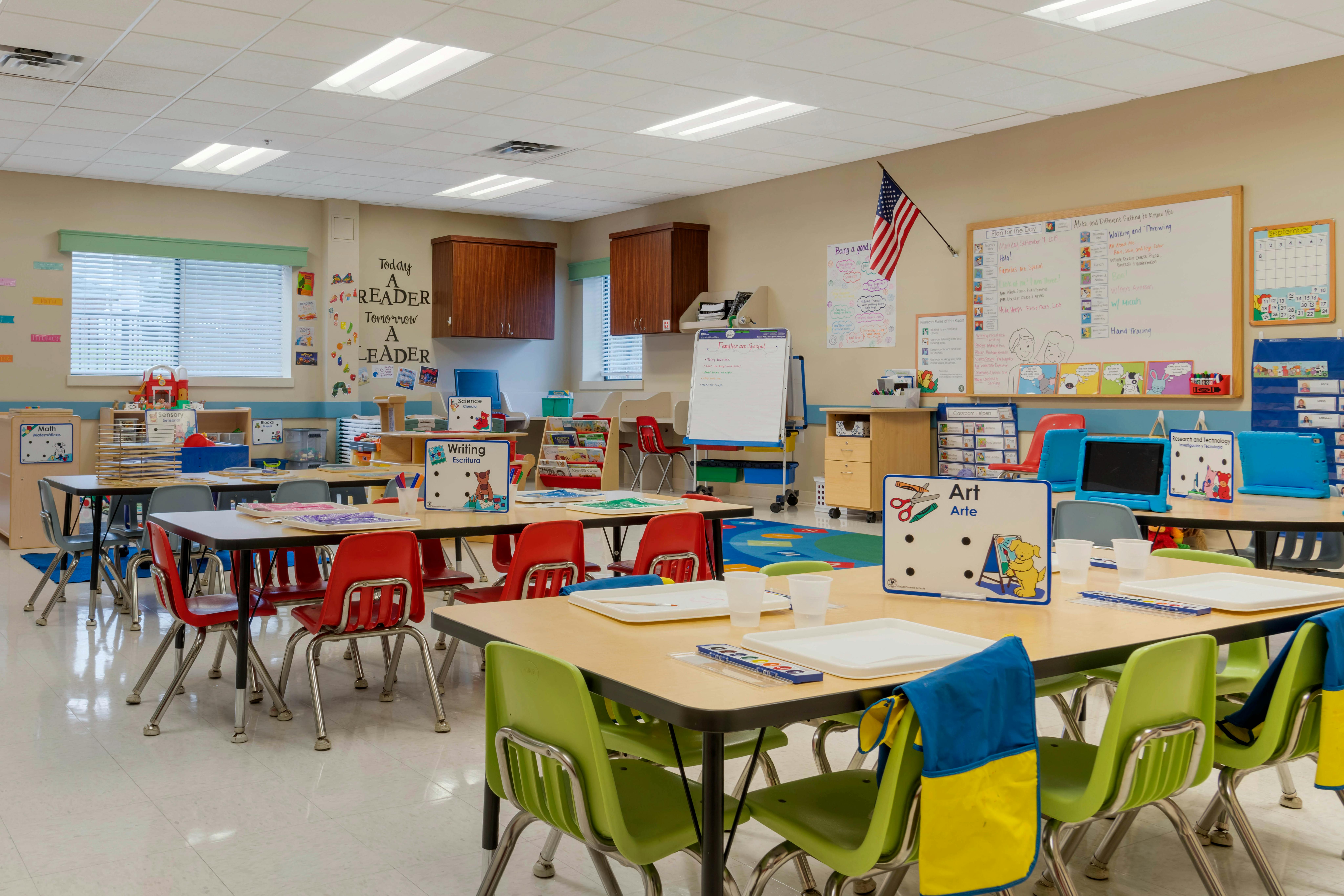 Empty classroom with small tables and chairs, whiteboards, and learning materials